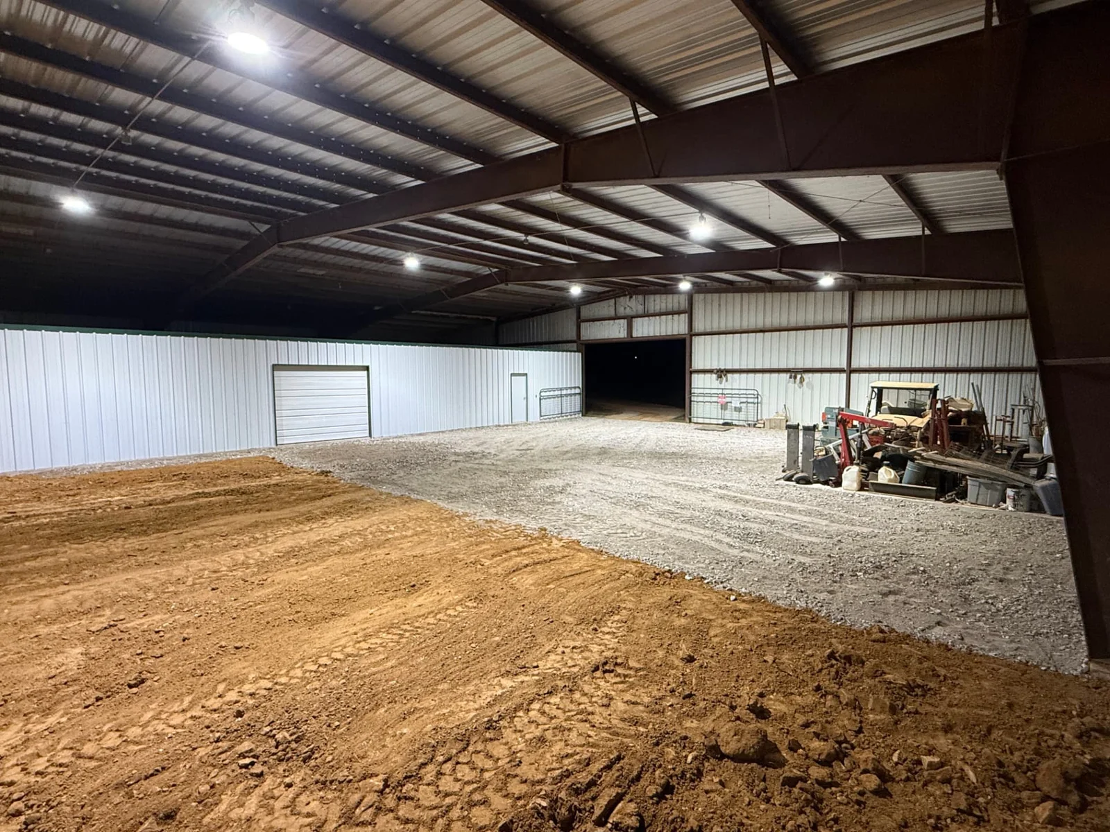 Interior of a covered metal building showing a graded flex base parking lot beside fresh select fill arena footing in Aubrey, Texas