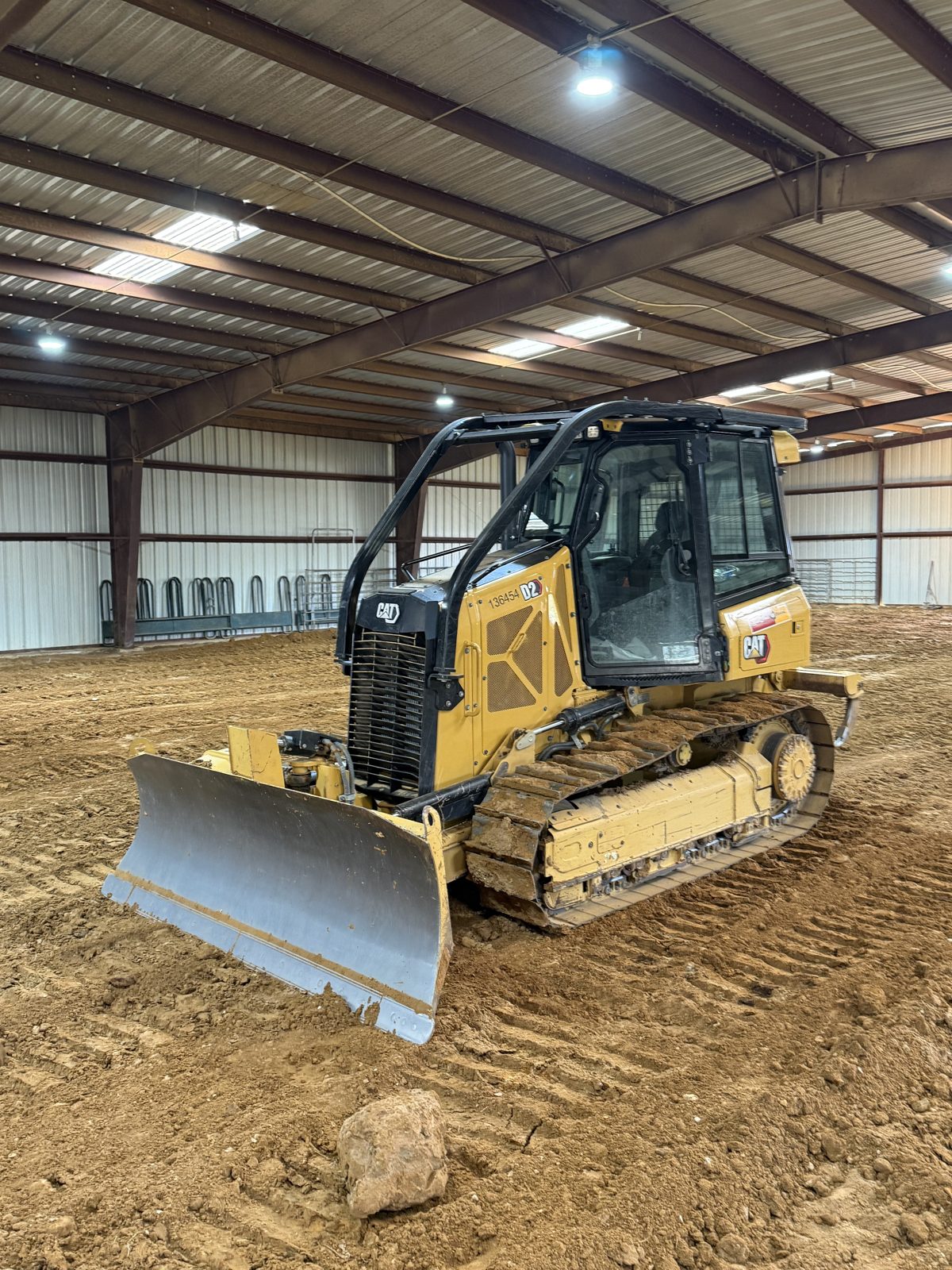 Dozer grading a dirt floor inside a metal building shell