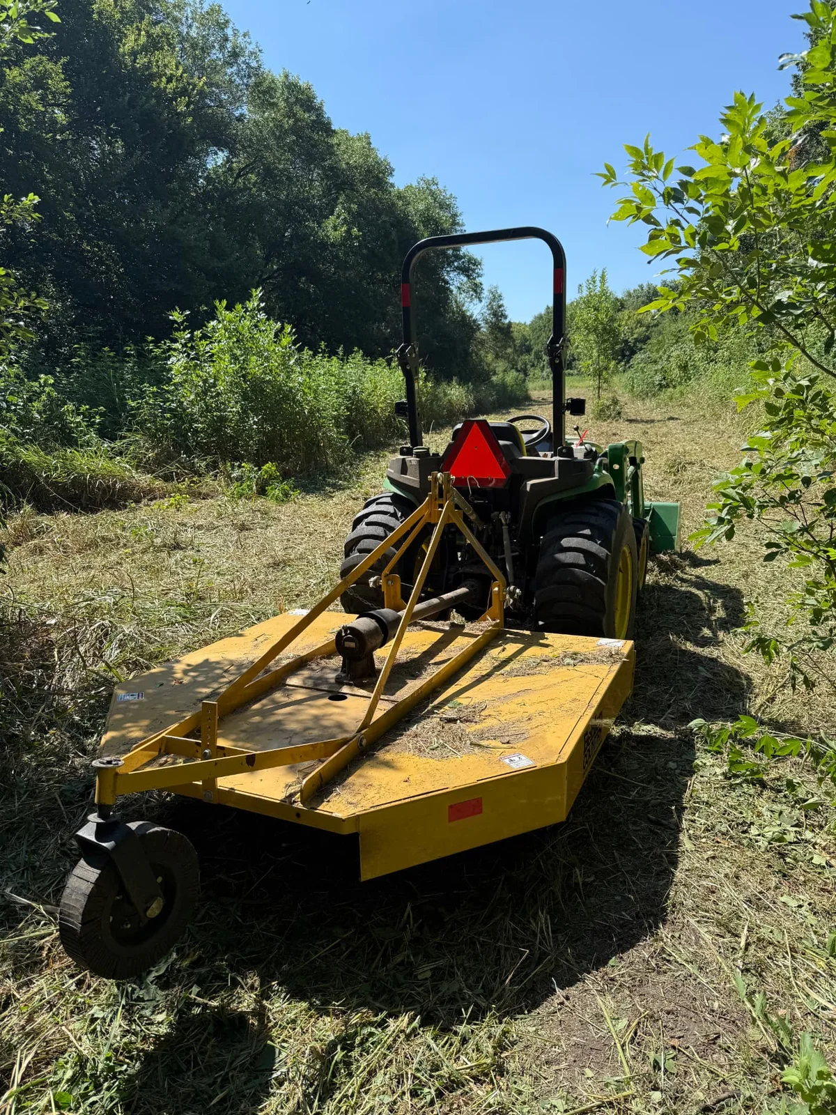 Tractor with a rotary cutter parked on cleared ground after brush removal