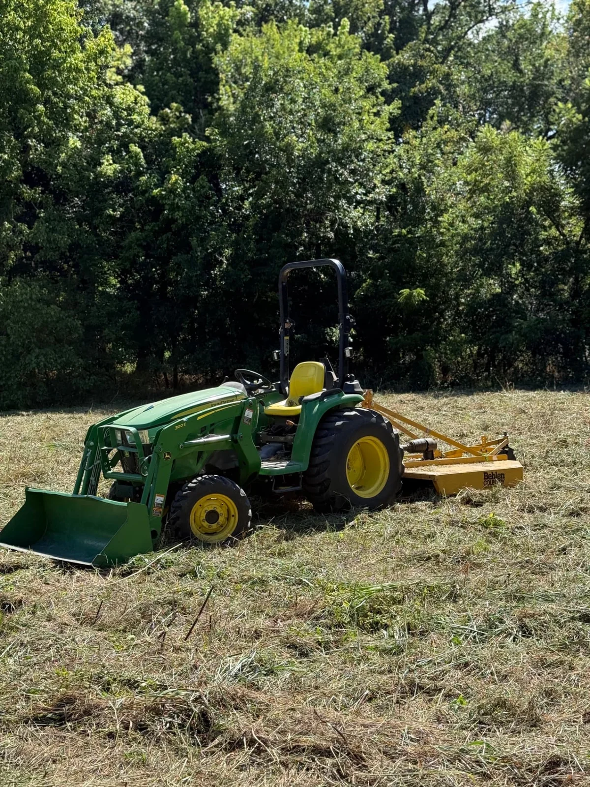 John Deere tractor with a rotary cutter mowing tall grass and weeds in Melissa, Texas